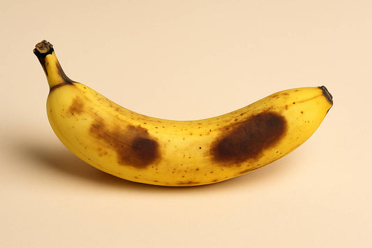 Close-up of a ripe yellow banana with large brown bruises on the peel, symbolizing imperfections, grief, and growth in the Danna Bananas journey.