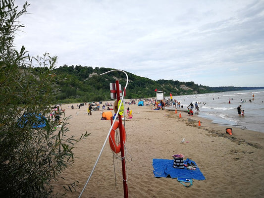 Summer beach day at Scarborough Bluffs with families, sand, lifeguard equipment, and Lake Ontario waves.