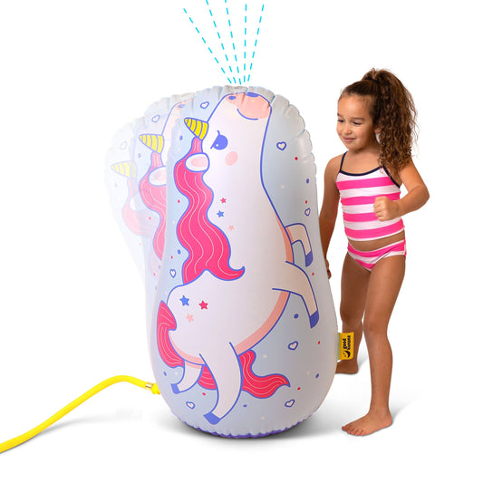 Little girl punching an inflatable unicorn sprinkler as water sprays from the top in a Canadian backyard