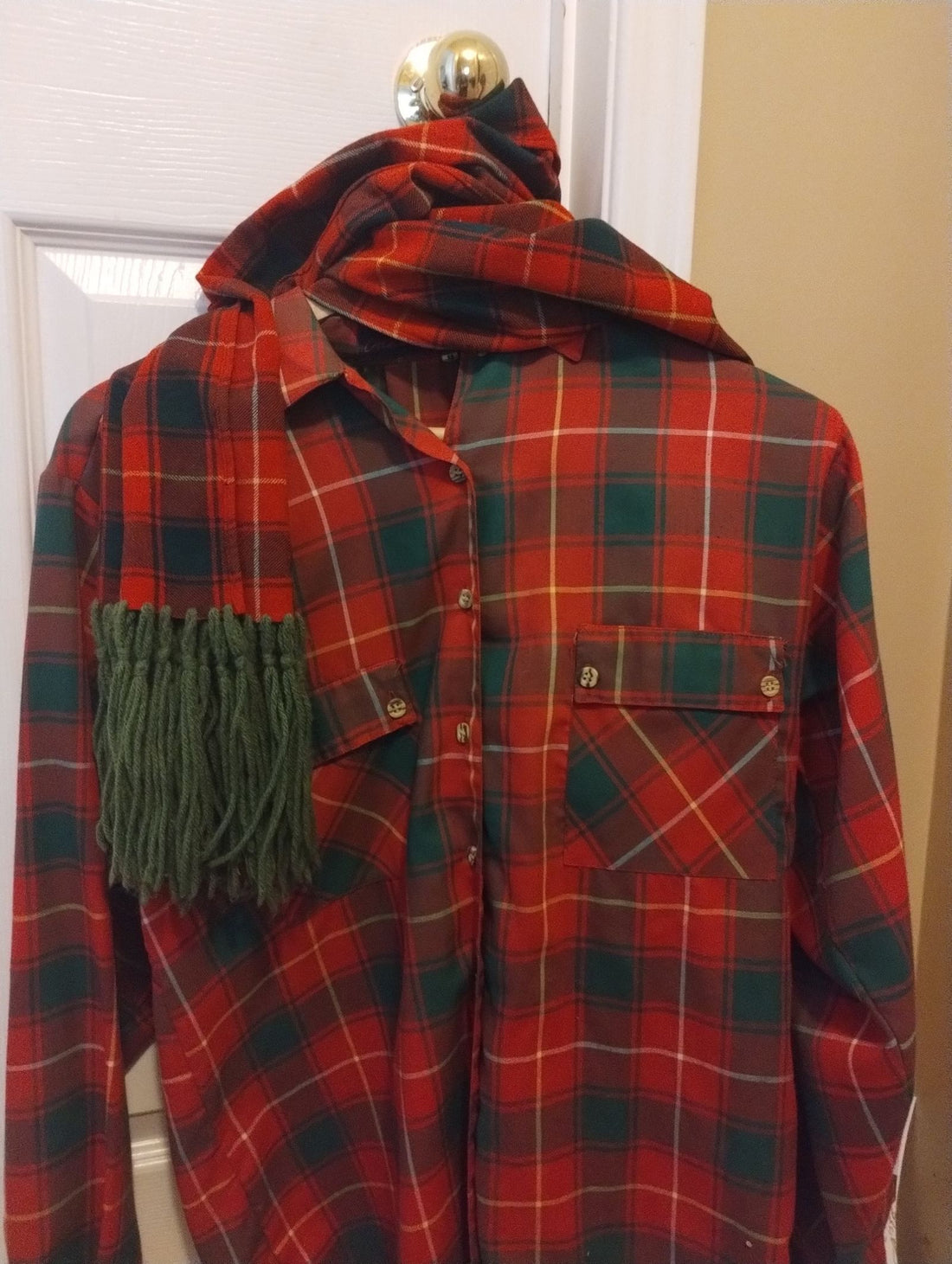 Red and green tartan shirt with matching scarf hanging on a door, celebrating Scottish heritage for Robbie Burns Day 2026
