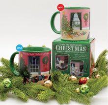 Two Twas the Night before Christmas Heat-Changing Mugs by Danna Bananas, one labeled "cold" and the other "hot," are placed beside a festive packaging box. Surrounded by pine branches and ornaments, these mugs make an ideal holiday gift as their design transforms with temperature.