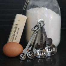 Guitar Measuring Spoons leaning on jar of sugar and with an egg and unsalted butter