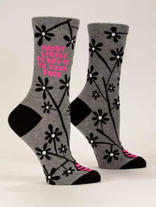 Danna Bananas' "Most Likely To Say It To Your Face" crew socks for women feature a gray design with black floral patterns, complemented by black heels and toes, and playful pink text. These novelty socks effortlessly combine humor with style.