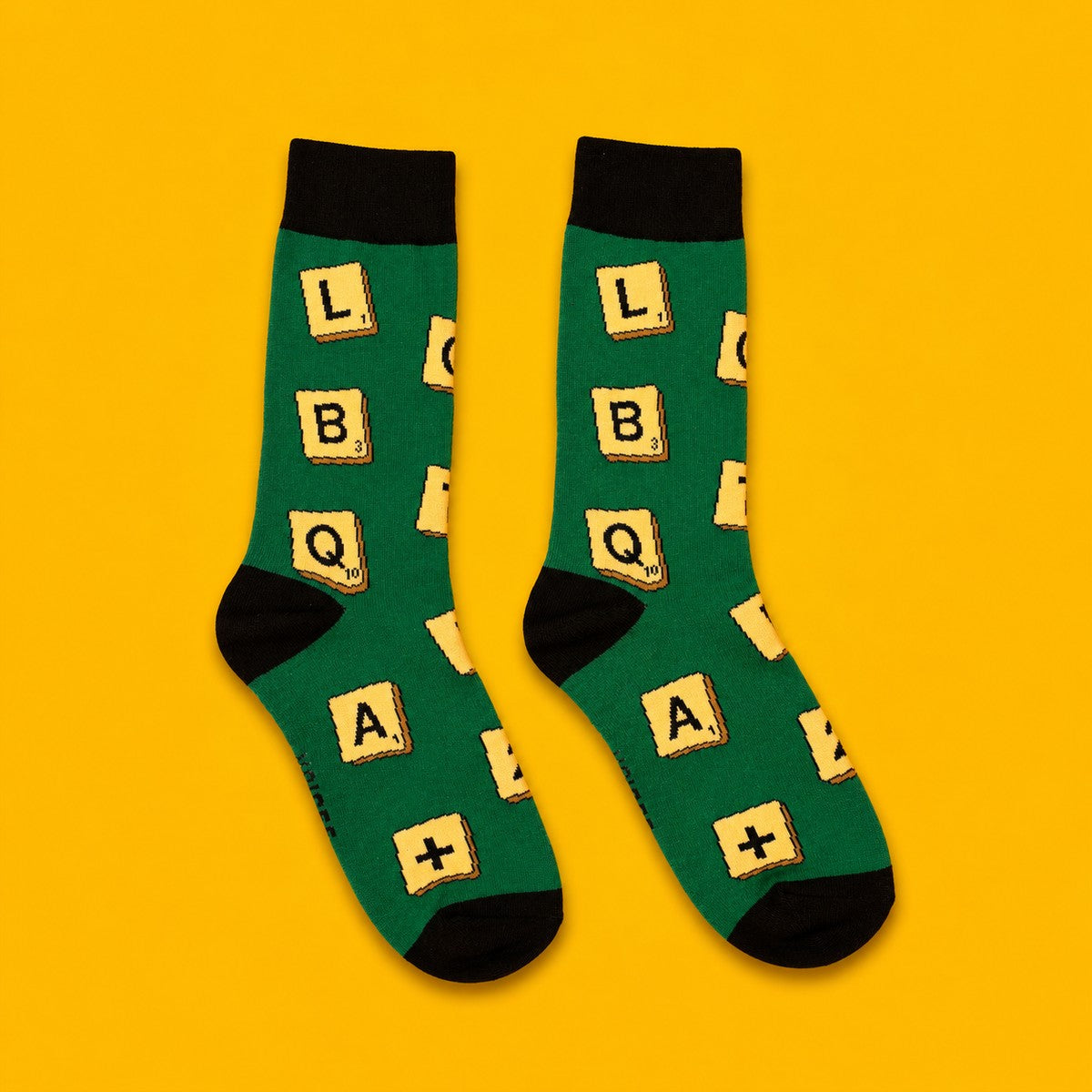 Scrabble Pride Socks with an LGBTQ+ letter tile design on a yellow background