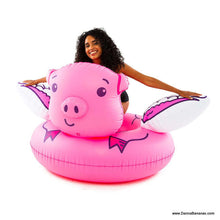 Woman sitting on a giant pink flying pig pool float – funny inflatable summer toy