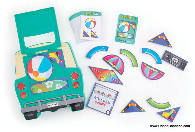 Image of the Road Trip Packing Puzzle by Outset Media, showcasing a green car case filled with vibrant beach-themed puzzle pieces and a stack of cards. This brainteaser game challenges your spatial reasoning skills with its curved and triangular shapes, including an "ICE COLD Drinks!" piece.