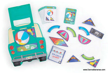 Image of the Road Trip Packing Puzzle by Outset Media, showcasing a green car case filled with vibrant beach-themed puzzle pieces and a stack of cards. This brainteaser game challenges your spatial reasoning skills with its curved and triangular shapes, including an "ICE COLD Drinks!" piece.