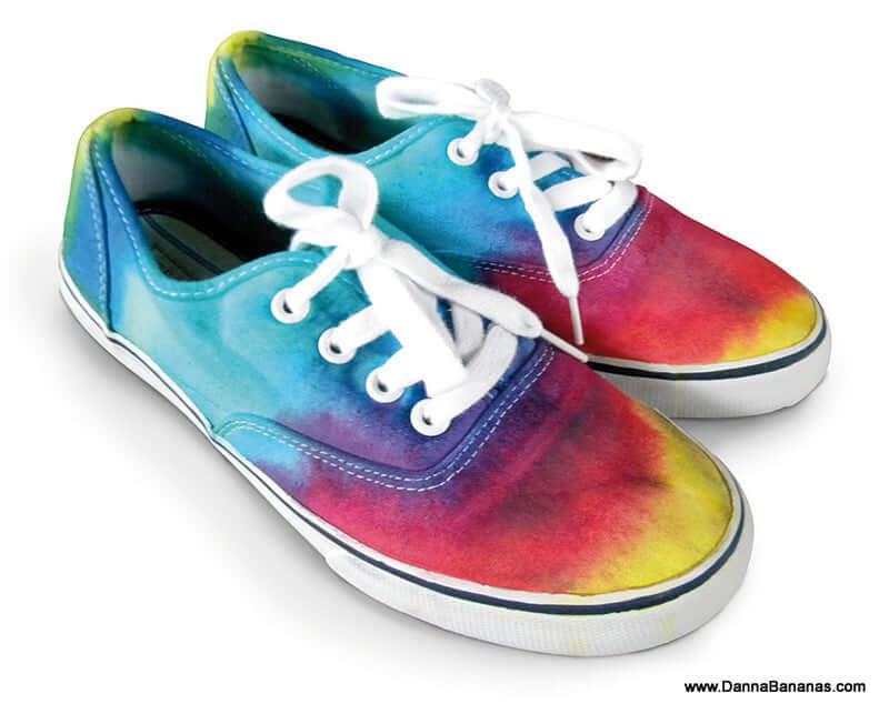 Introducing the Outset Media Tie Dye Kit, perfect for creating vibrant sneakers in a non-toxic tie-dye pattern featuring shades of blue, green, yellow, red, and pink. Ideal for sensitive skin, this kit includes hypo-allergenic materials to ensure a comfortable finish when applied to your shoes with white laces and a sleek white sole.