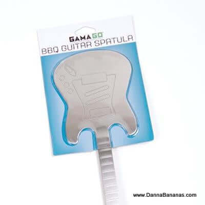 The GAMAGO BBQ Guitar Spatula features a stainless steel flipper and a handle shaped like a guitar neck. Its blue and white packaging includes branding, website info, and confirms that it is dishwasher safe for easy cleaning.