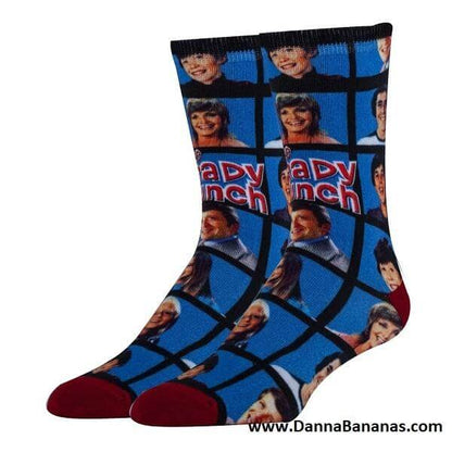 The Brady Bunch Women's Crew Socks by Danna Bananas feature a vibrant grid of retro-style portraits along with the iconic "Brady Bunch" in bold red letters. These novelty socks boast red toes, dark cuffs, and a website URL at the bottom, making them an ideal choice for any fan of retro television.
