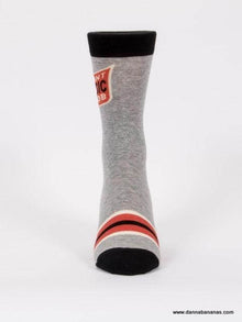 Meet Danna Bananas' Giant Music Snob Men's Crew Socks - a single gray sock with a red patch and white text at the top, black toe and cuff, two horizontal red stripes near the ankle, and set against a plain white background. Perfect for music-loving dads!.