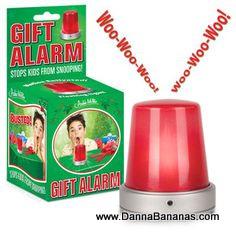 Both the product box and the actual product are displayed. The box is labeled "Gift Alarm: Stops Kids from Snooping!" and showcases an image of a surprised child with the motion-activated alarm. The item itself is a red security alarm light that emits a "Woo-Woo-Woo!" sound, making it an excellent holiday gift idea. Find out more at www.DannaBananas.com, courtesy of Danna Bananas.
