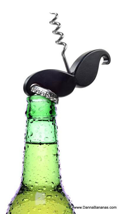 A green glass beer bottle with condensation is topped with a Handlebar Corkscrew & Bottle Opener from Danna Bananas, in the process of removing the metal cap. The background is plain white, and the website "www.DannaBananas.com" is visible at the bottom right, supporting Movember Canada.
