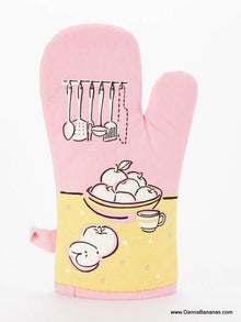 The "I've Got A Knife Oven Mitt" by Danna Bananas is a charming pink kitchen accessory with quilted insulation. It features a fruit bowl, sliced fruit, and cup on a sunny yellow background, with elegant kitchen utensils hanging above the bowl.