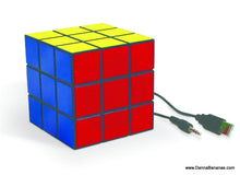 The Danna Bananas Rubik's Cube Speaker is a colorful and adaptable audio device with blue, yellow, and red sides. Its design evokes the nostalgic appeal of a classic puzzle toy while featuring an attached cable equipped with both a USB and an audio jack.