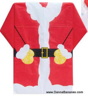An image showcases a rectangular Christmas-themed tablecloth designed to resemble Santa Claus's red suit with white trim, a black belt with a gold buckle, and white gloves. Ideal for your holiday table decor, it pairs perfectly with Danna Bananas' Santa Suit Holiday Napkins. The website "www.DannaBananas.com" is visible in the bottom right corner.