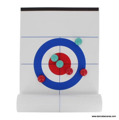 The Tabletop Curling Game by Danna Bananas features a magnetic curling sheet displaying three red stones and two green stones on the target, with a red stone nearest to the center. Ideal for tabletop play, this board is partially rolled at the bottom.