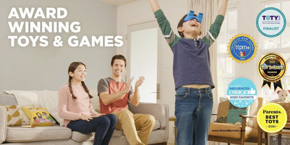In the cozy living room, a joyful family revels in a board-game night featuring The UpsideDownChallenge Game by Danna Bananas. With his arms raised in celebration, a boy sports blue upside-down goggles on his head. A woman and man sit on the couch, applauding enthusiastically. The image showcases various award badges in recognition of the game.