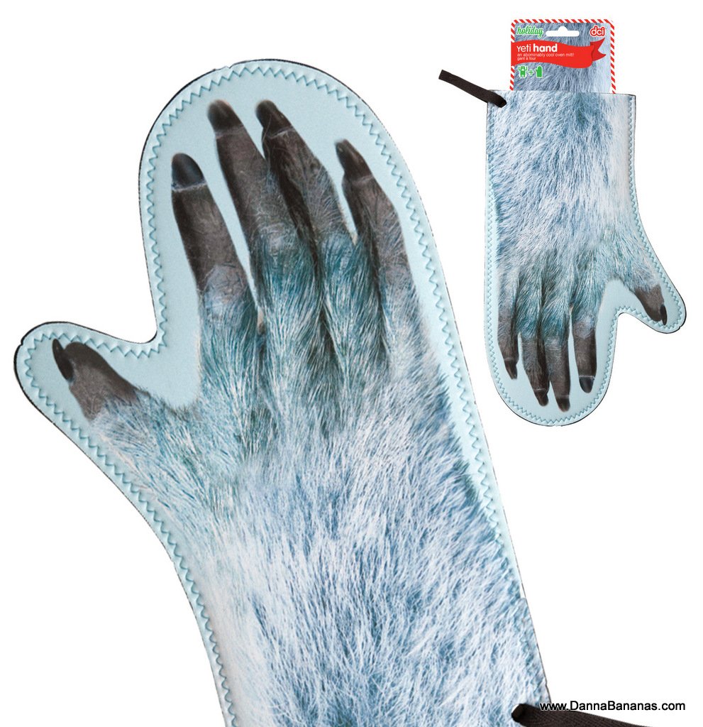 The Yeti Hand Oven Mitt by Danna Bananas is a light blue mitt designed to resemble a furry animal paw, complete with black claws. It features detailed fur graphics and stitching along the edges, and includes a small tag at the top displaying the branding information.